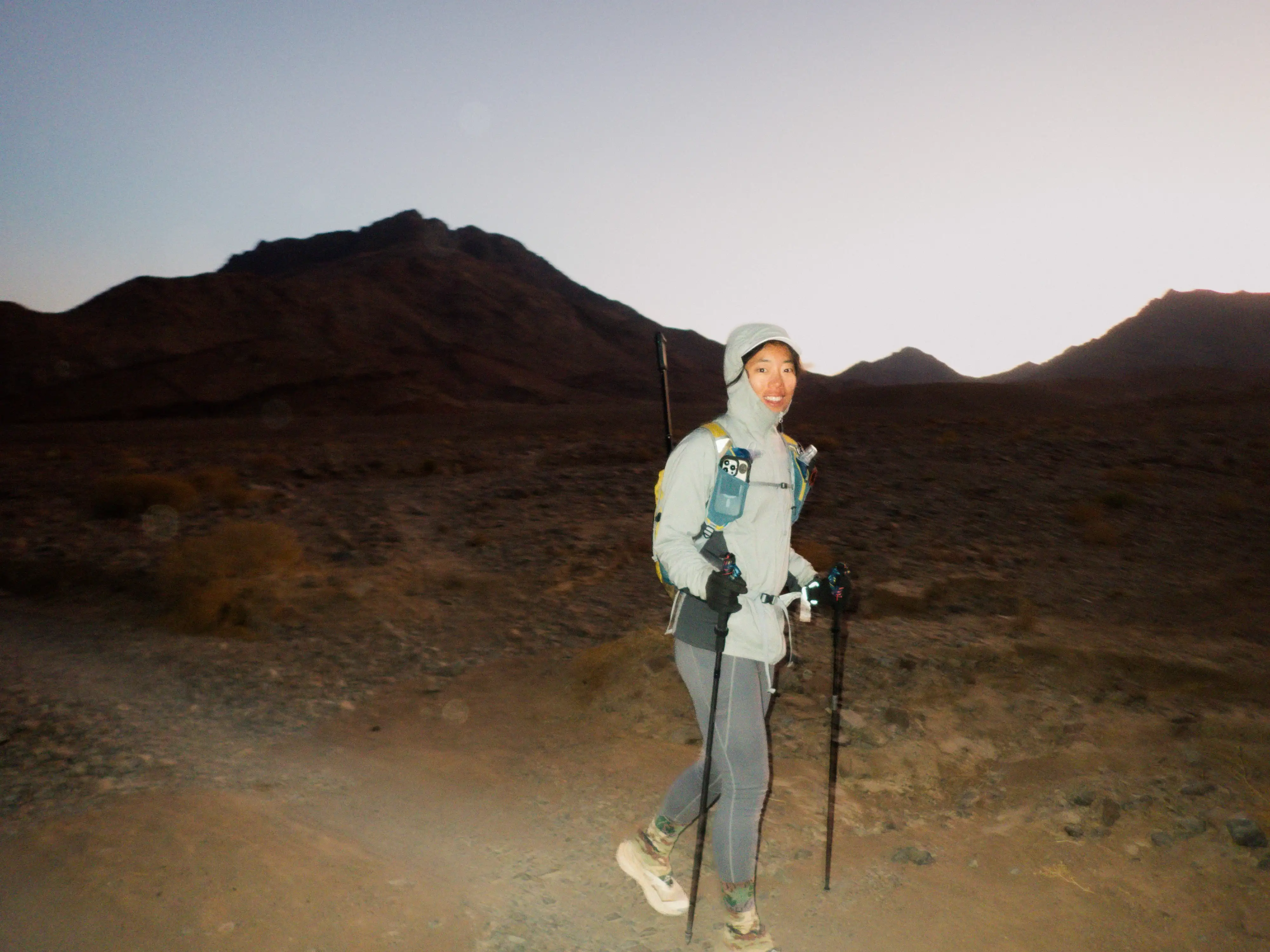 Ria Xi mid-stride on a dusty trail, determination visible in her posture as she runs through challenging terrain